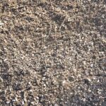 Close-up of ClayBuster Landscaping Soil Blend, a gritty gray-brown garden soil