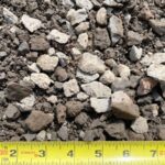 3/4″ Minus Crushed Gravel with angular gray and tan rock and fines next to a tape measure